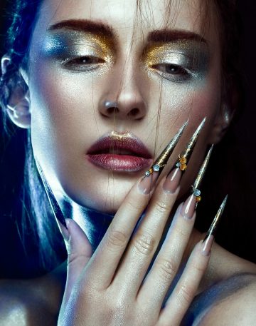 Beautiful girl with creative golden and silver glitter make-up, long nails art. beauty face.