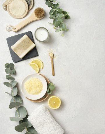 Flat lay organic yellow sea salt with lemon, soap, brush, sponge and eucalyptus branch