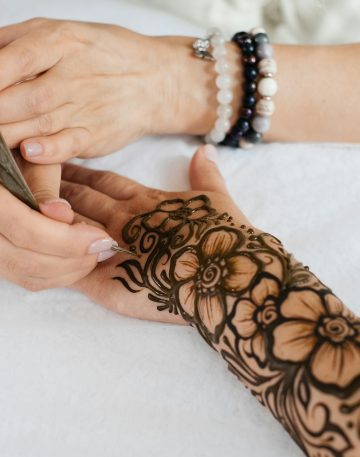 Henna tattoo on woman hands, artist drawing Arabic mehndi