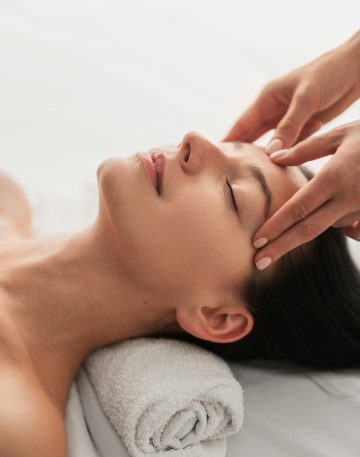 Relaxed young lady lying on massage table during beauty procedure