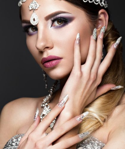 Woman in makeup and hairstyle with long nails with design